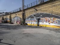 a building covered with lots of different graffiti paint on it's exterior wall next to a brick road