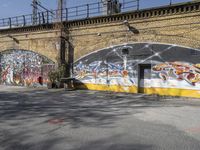 a building covered with lots of different graffiti paint on it's exterior wall next to a brick road