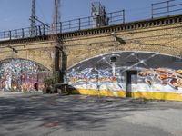 a building covered with lots of different graffiti paint on it's exterior wall next to a brick road