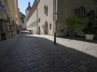 a cobblestone street with a clock tower on it and graffiti all over the wall