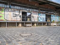 the train station is covered in graffiti and art as well as parked motorcycles and buses