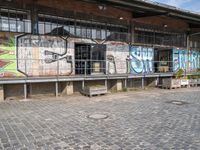 the train station is covered in graffiti and art as well as parked motorcycles and buses