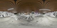 a large room with a curved ceiling and a floor made of cement and wooden planks