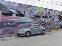 the light blue volkswagen beetle has graffiti on it and is parked on the street side