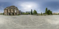 360 - view photo of an old church at a park with people walking and riding on their bicycles