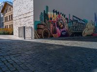 a graffiti filled street with buildings and brick sidewalks on the corner of a cobblestone road