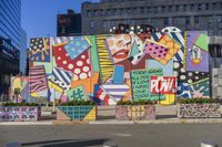 colorful, patterned graffiti painted on the side of an office building near some trashcans