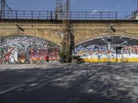 a grafit mural near an old brick wall near a bridge with graffiti all over it