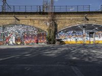 a grafit mural near an old brick wall near a bridge with graffiti all over it