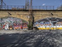 a grafit mural near an old brick wall near a bridge with graffiti all over it