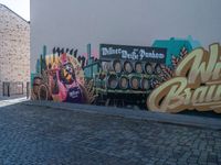 mural of beer being painted on a wall with people walking by it at a sidewalk