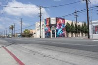 a large graffiti painted on the side of a building is in front of a city street