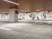 a concrete parking lot in an empty space with painted murals on the walls and ceiling