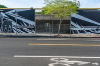 an empty street with a bike lane and wall paintings on the walls of its