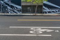 an empty street with a bike lane and wall paintings on the walls of its