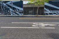 an empty street with a bike lane and wall paintings on the walls of its