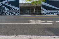 an empty street with a bike lane and wall paintings on the walls of its