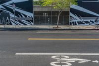 an empty street with a bike lane and wall paintings on the walls of its