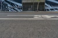 an empty street with a bike lane and wall paintings on the walls of its