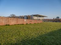 this grass field has been cut short to cover the area in the distance, and it is a grassy area next to an old building