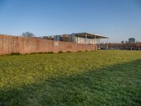 this grass field has been cut short to cover the area in the distance, and it is a grassy area next to an old building