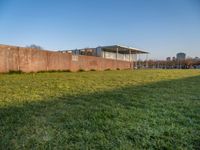 this grass field has been cut short to cover the area in the distance, and it is a grassy area next to an old building