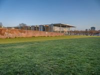 this grass field has been cut short to cover the area in the distance, and it is a grassy area next to an old building