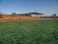 this grass field has been cut short to cover the area in the distance, and it is a grassy area next to an old building