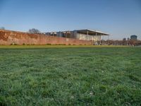 this grass field has been cut short to cover the area in the distance, and it is a grassy area next to an old building