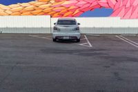 a car parked in front of a painted mural of a feather on the side of a building