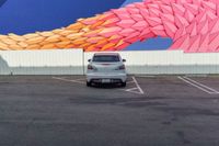 a car parked in front of a painted mural of a feather on the side of a building