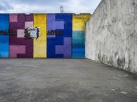 a graffiti wall and graffiti art with graffiti in an empty parking lot area in front of a concrete building