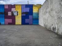 a graffiti wall and graffiti art with graffiti in an empty parking lot area in front of a concrete building