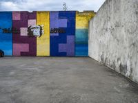 a graffiti wall and graffiti art with graffiti in an empty parking lot area in front of a concrete building