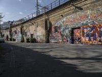 the graffiti is all over the building and walls on this side walk, with its colors