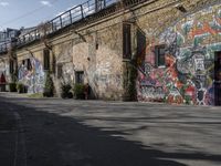 the graffiti is all over the building and walls on this side walk, with its colors