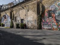 the graffiti is all over the building and walls on this side walk, with its colors