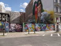 a wall painted with images of people in many colors and patterns on the walls next to a bike and car