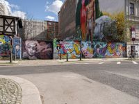 a wall painted with images of people in many colors and patterns on the walls next to a bike and car