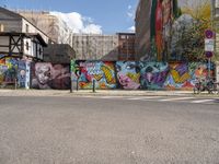 the street is lined with murals and buildings around it and people walking down the sidewalk