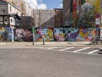 the street is lined with murals and buildings around it and people walking down the sidewalk