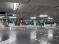 an empty parking lot with graffiti painted on the walls in different languages and colors with a single white arrow pointing down at it