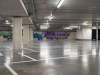 a empty parking garage with graffiti painted on the walls and concrete floors and a person walking by