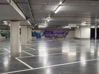 a empty parking garage with graffiti painted on the walls and concrete floors and a person walking by