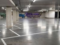 a empty parking garage with graffiti painted on the walls and concrete floors and a person walking by