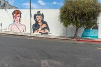 the mural on this wall is depicting mick and rod herring with music headphones and rock star hair