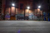 an empty parking lot has graffiti all over it in the dark night time, with the lights on