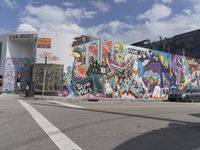 a graffiti wall in front of a building with a mural on the side of it