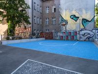 a basketball court with some graffiti painted on it in front of an apartment building in germany