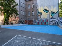 a basketball court with some graffiti painted on it in front of an apartment building in germany